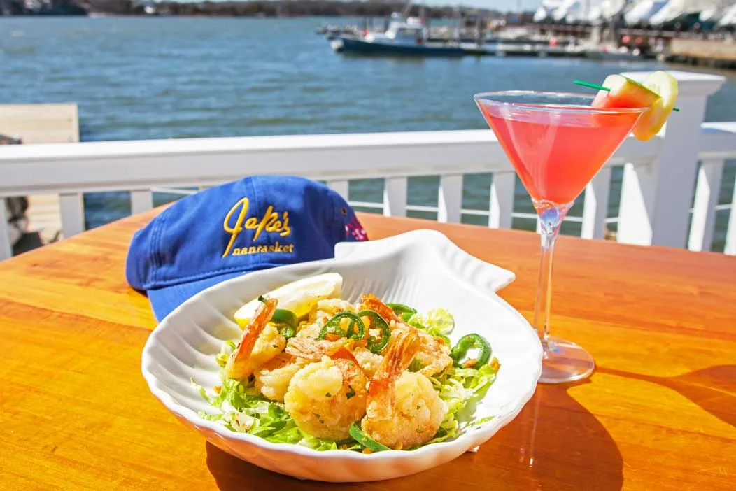 Jake's branded hat, shrimp dish, and cocktail on the waterfront deck